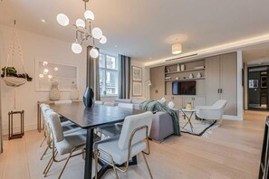 A modern kitchen with a dining area, large windows, and a hanging light fixture. - Three-Bedroom Superior Apartment (London)