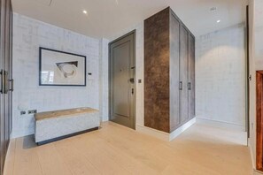 A room with a bench, a door, and a cabinet. - Four Bedroom Duplex Penthouse (London)