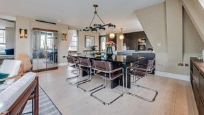 Een moderne keuken met een centraal eiland, roestvrijstalen apparatuur en een eetgedeelte met een zwarte tafel en metalen stoelen.
