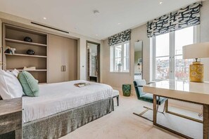 Un dormitorio moderno con cama, estanterías empotradas, escritorio y un ventanal grande.