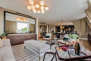 Un salon moderne avec un grand miroir, un coin repas et une cuisine en arrière-plan.