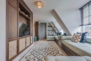 Une chambre de style loft moderne, avec un lit en mezzanine, un téléviseur intégré et un tapis à motifs.