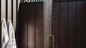 Una ducha con chorro vertical, un perchero y una plataforma de madera.