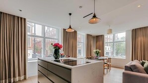 Et moderne køkken med en central ø, store vinduer og et spiseområde med en sofa.