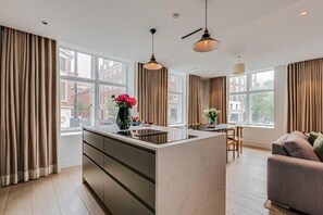 A modern kitchen with a central island, large windows, and a dining area with a sofa. - Two-Bedroom Superior Apartment (London)