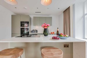 Een moderne keuken met een centraal eiland, inbouwapparatuur en een bloemenvaas.