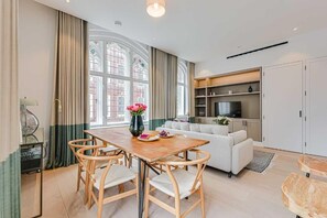 Een moderne woonkamer met een eettafel, stoelen, een bank en een televisie.