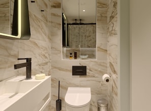A modern bathroom with a white sink, black faucet, and a toilet. - Standard Studios in South Kensington (London)