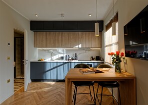 A modern kitchen with a central island, wooden cabinets, and a dining area with a wooden table and bar stools. - Standard Studios in South Kensington (London)