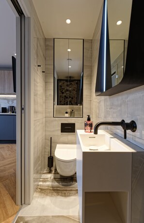 A modern bathroom with a white sink, black faucet, and a large mirror. - Standard Studios in South Kensington (London)