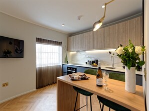 A modern kitchen with a wooden countertop, a wine bottle, and a vase of flowers. - Standard Studios in South Kensington (London)
