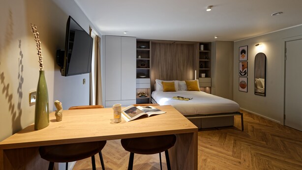 Ein modernes Schlafzimmer mit Bett, Nachttischen, einem Fernseher und Holzboden.