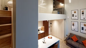 Un interior moderno con una escalera, una zona de comedor y un sofá.
