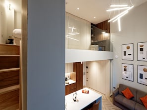 A modern interior with a staircase, a dining area, and a sofa. - Duplex One Bedroom Apartment (London)