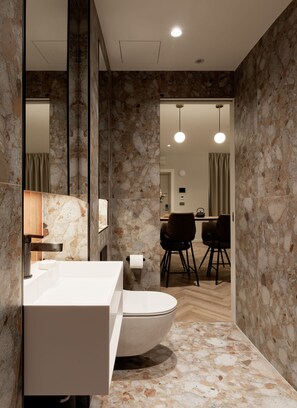 Un baño moderno con una bañera independiente, un espejo grande y una pared de mármol.