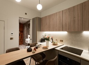 Eine moderne Küche mit Holzausstattung, einer zentralen Kochinsel mit Sitzgelegenheiten, einem eingebauten Backofen und einem kleinen Spülbecken.