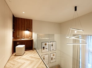 Un baño moderno con tocador de madera, cabina de ducha de vidrio y lámpara colgante.