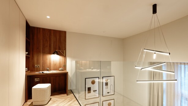 Een moderne badkamer met een houten wastafelmeubel, een douchecabine met glazen wanden en een hanglamp.
