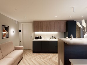 A modern kitchen with a central island, dark cabinets, and a light-colored countertop. - Superior Studio in Notting Hill (London)