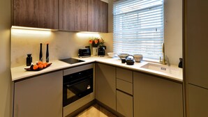 Een moderne keuken met houten kastjes, een inbouwoven, een spoelbak en een raam met zonwering.