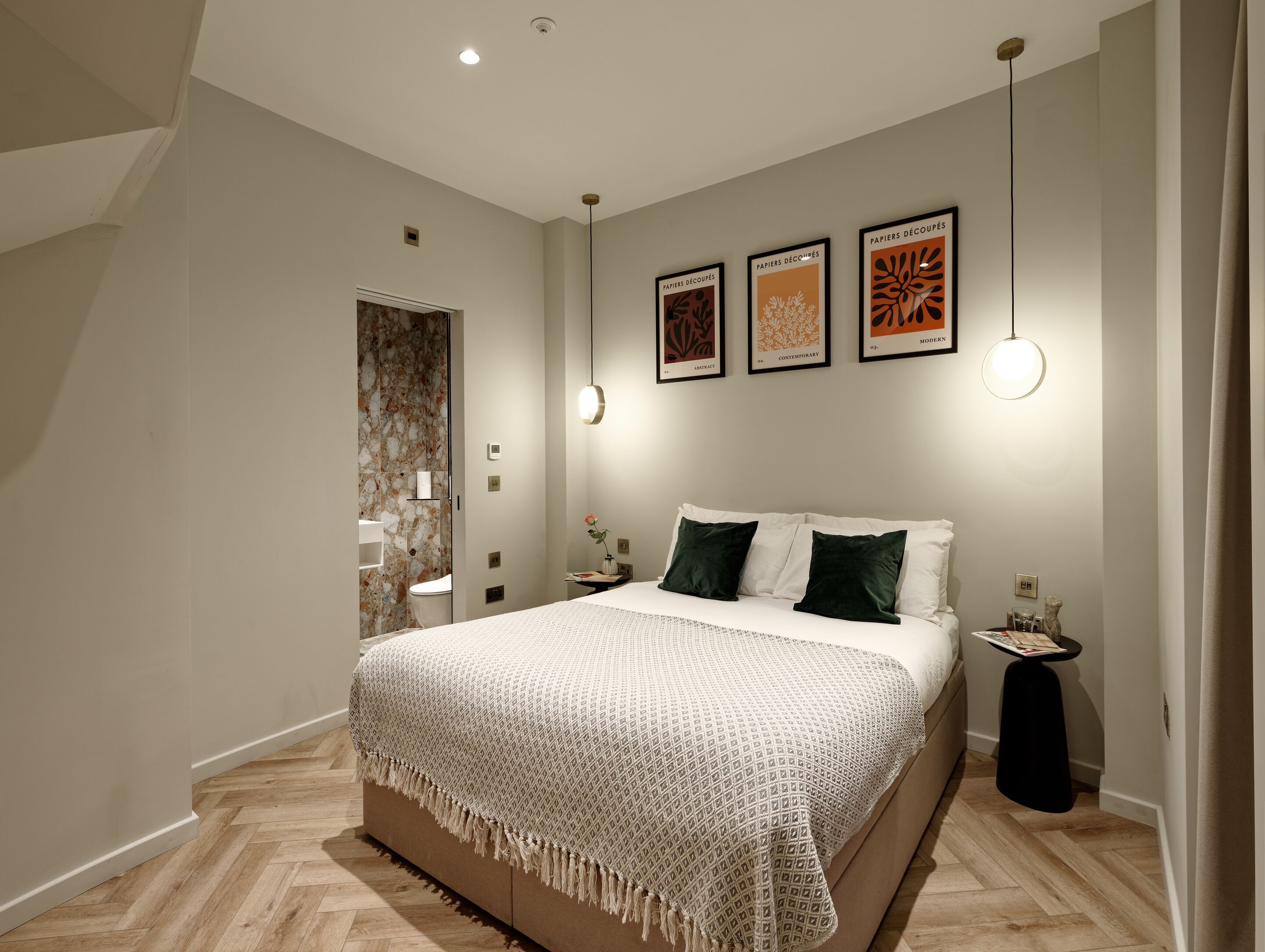Een moderne slaapkamer met een groot bed, een nachtkastje en een wandlamp.