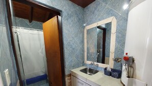 A bathroom with a shower, a sink, and a mirror. - Aparment Camila 2 (El Calafate)