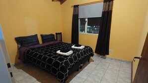 A bedroom with a bed, a window with curtains, and a tiled floor. - Aparment Camila 2 (El Calafate)