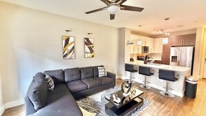 A modern living room with a sectional sofa, a coffee table, and a kitchen in the background. - Luxury buckhead apartment (Atlanta)
