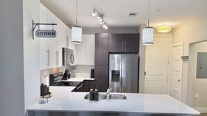 A modern kitchen with a central island, stainless steel appliances, and pendant lighting. - Luxury buckhead apartment (Atlanta)
