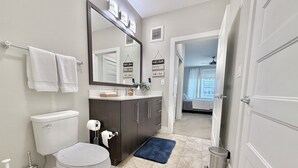 A bathroom with a toilet, sink, mirror, and blue rugs. - Luxury buckhead apartment (Atlanta)