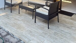 A modern outdoor seating area with wicker furniture and a glass partition.