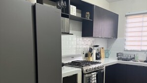 A modern kitchen with a stainless steel refrigerator, a gas stove, and black cabinets.