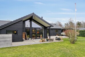 A modern house with a large glass door, a covered porch, and a flagpole in the yard. - New holiday home close to the beach (Middelfart)