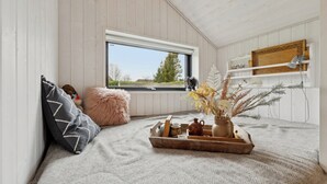 Una camera mansardata accogliente con una finestra, uno scaffale in legno, un cuscino soffice, un vassoio con oggetti decorativi e un vaso con fiori secchi.
