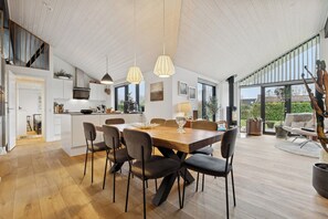A spacious kitchen with a dining area, wooden floors, pendant lighting, and large windows. - New holiday home close to the beach (Middelfart)