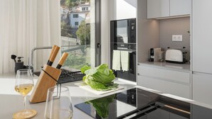 A modern kitchen with a large window, a built-in oven, and a toaster. - Calheta Hills IV – Apartment with Sea View (Calheta)