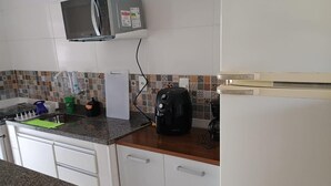 Eine Küche mit weißen Schränken, einer Mikrowelle, einem Toaster und einem Kühlschrank.