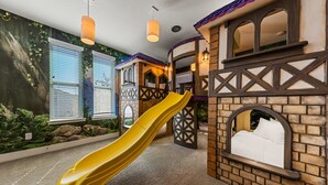 A children's play area with a yellow slide, playhouse, and a mural of a forest scene. - 8 Br Magical Themed Villa Close To Disney (Kissimmee)