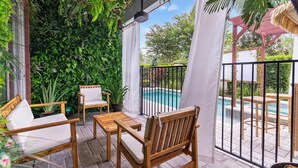 A patio with wooden furniture, a pool, and lush greenery. - 8 Br Magical Themed Villa Close To Disney (Kissimmee)