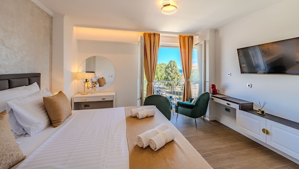 A hotel room with a large bed, a desk, a chair, a TV, and a balcony view. - Zaratino Room 4 in Zadar (Zadar)