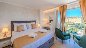 A hotel room with a bed, bedside tables, a chair, a small table, and a balcony with a view of buildings. - Zaratino Room 4 in Zadar (Zadar)