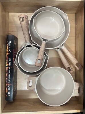 A wooden box containing a set of cookware including a frying pan, a saucepan, and a pot, along with a box labeled "Premium Barbecue Tool Set". - El Nido Getaway (Denver)