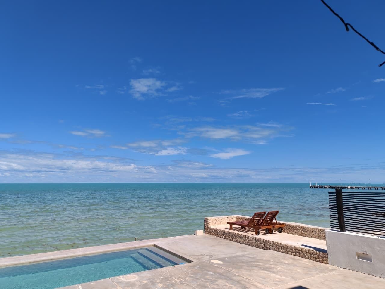 A pool with lounge chairs and a view of the ocean.