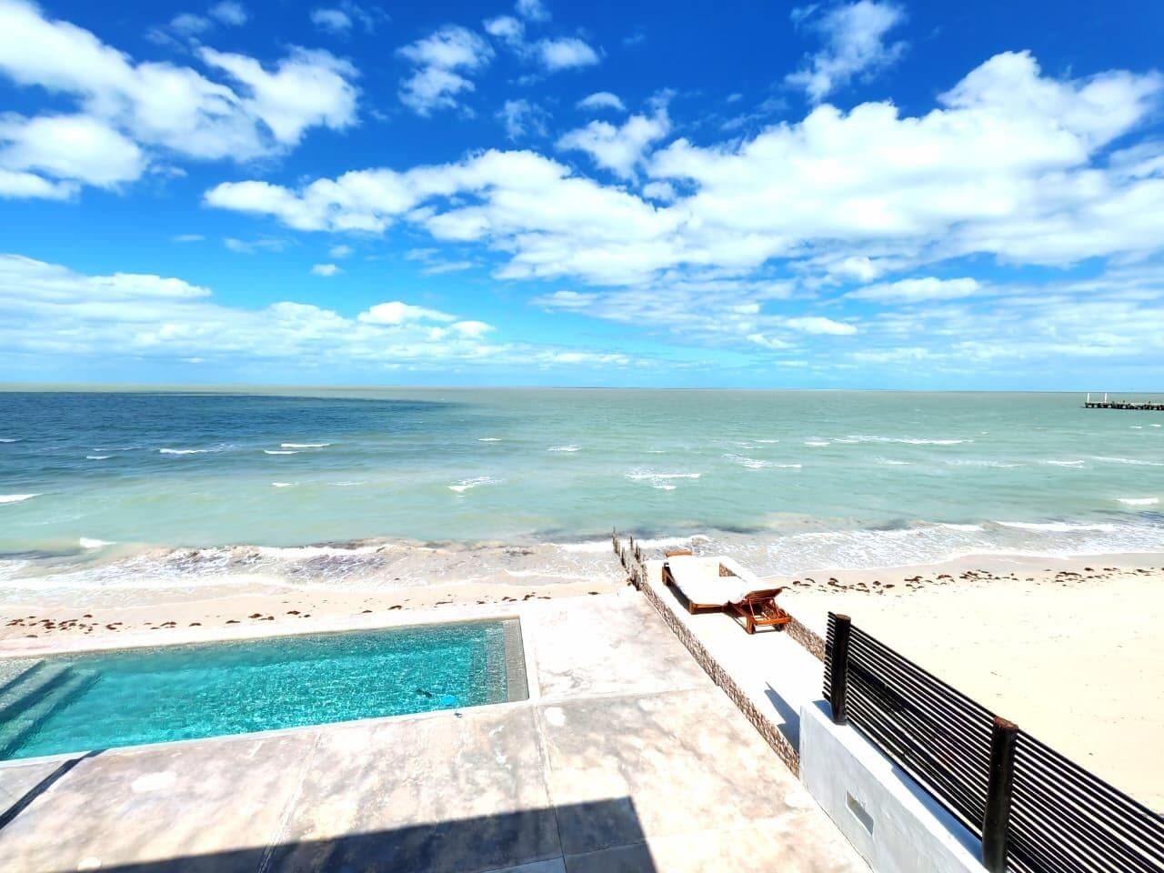 Une piscine située au bord de la plage, offrant une vue sur l’océan et un ciel dégagé.