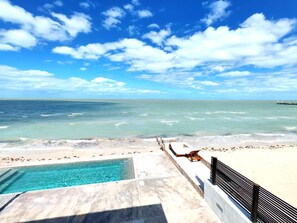 Ein Pool am Strand mit Blick auf das Meer und einem wolkenlosen Himmel.