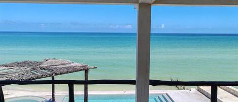 A balcony with a view of the ocean and a pool.
