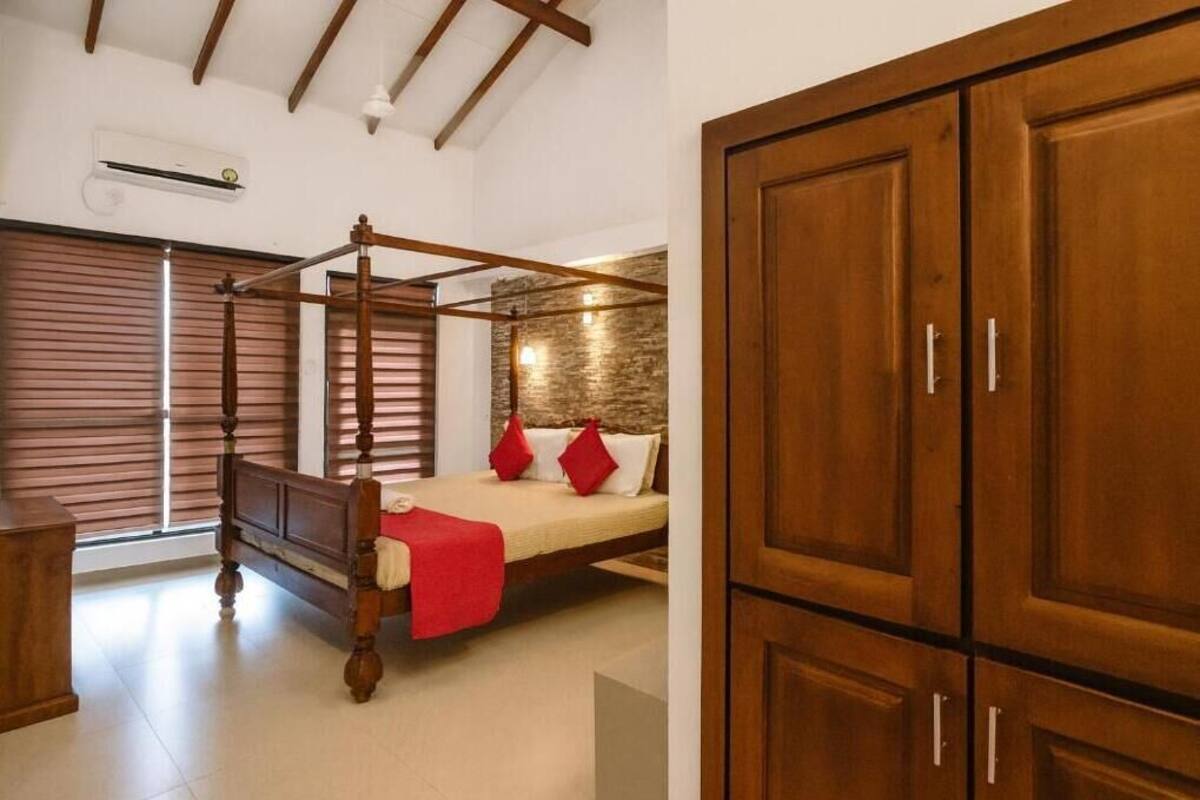 Una camera da letto con un letto a baldacchino, un'armadio in legno e una finestra con persiane.