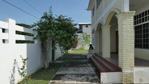 A building with a white exterior, a small garden with a tree, and a statue on the steps.