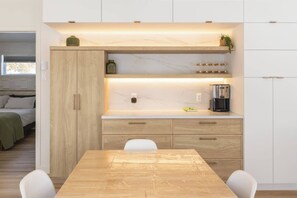 Eine kleine Küche mit Holztisch, weißen Schränken und einer eingebauten Mikrowelle.