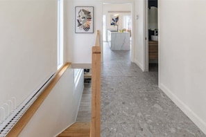 Ein modernes Interieur mit Treppe, einer Küchenzeile und einem Flur, der zum Badezimmer führt.